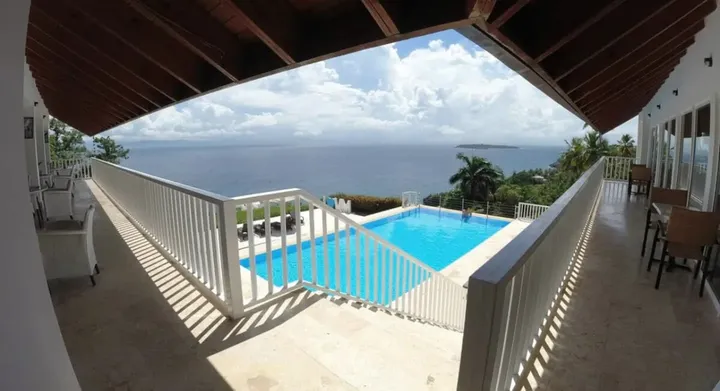 Pool seen from a covered terrace with the bay beyond